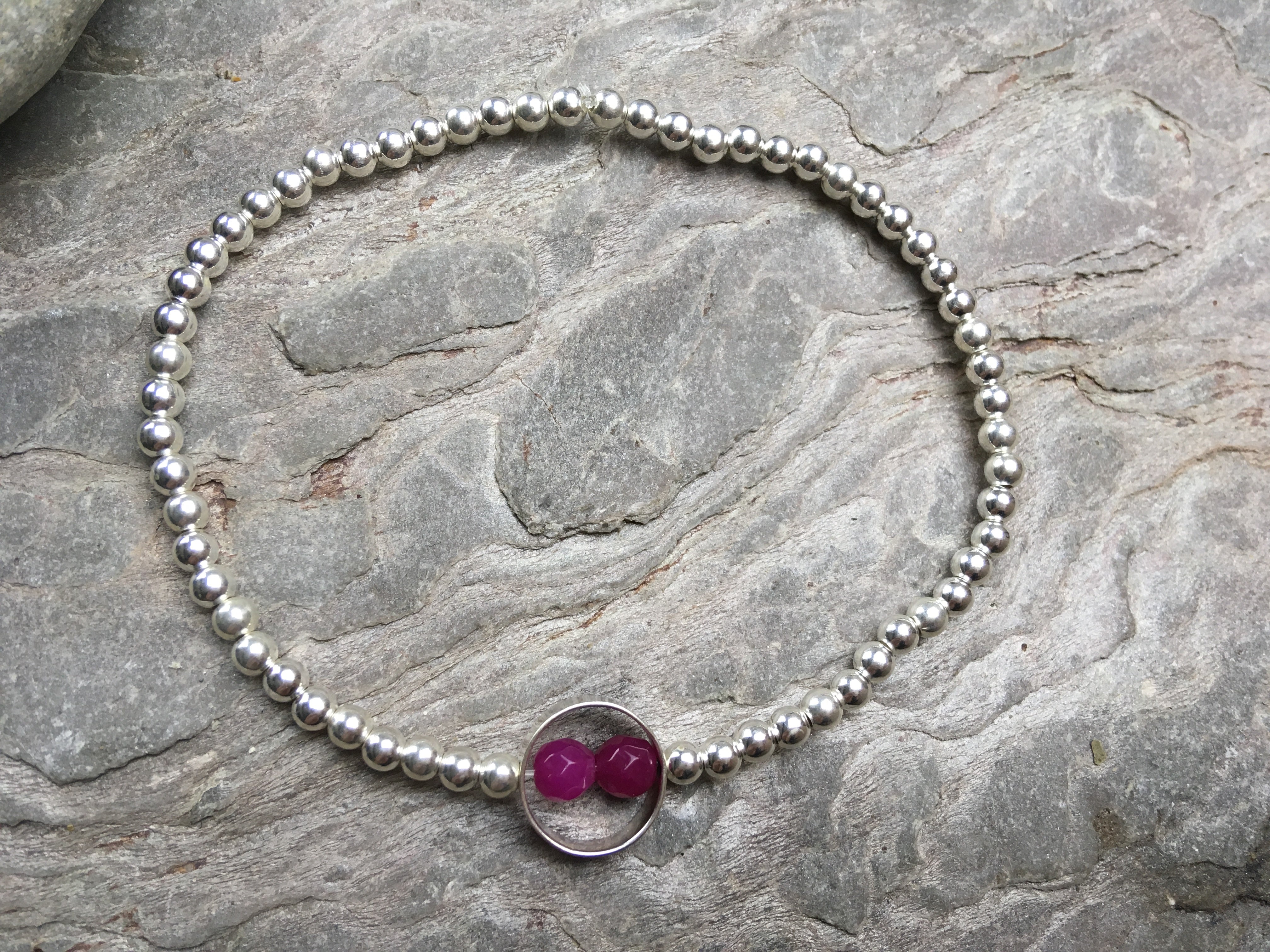 Silver beaded bracelet with double pink stone in ring.