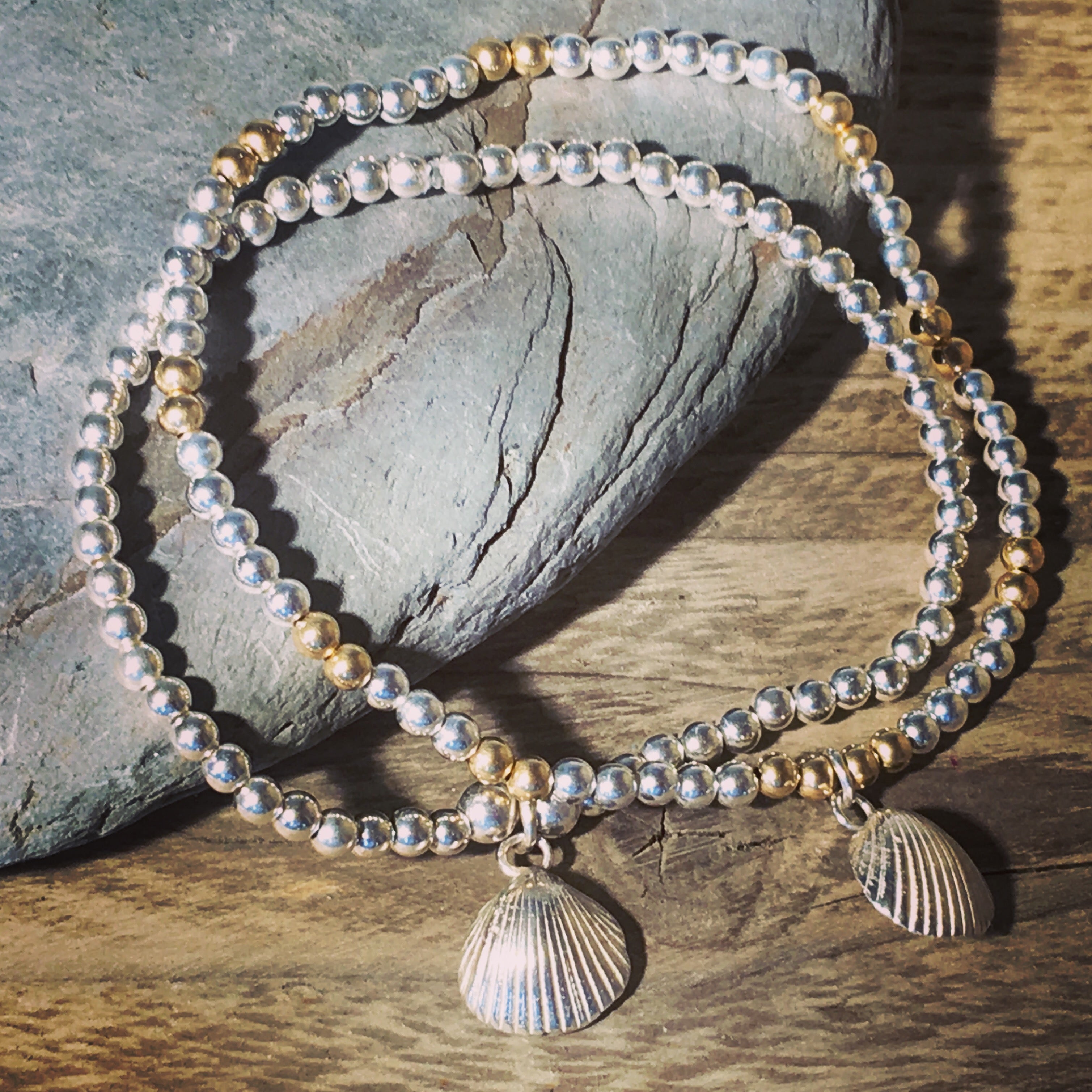 Silver and gold beaded bracelet with cockle shell charm.